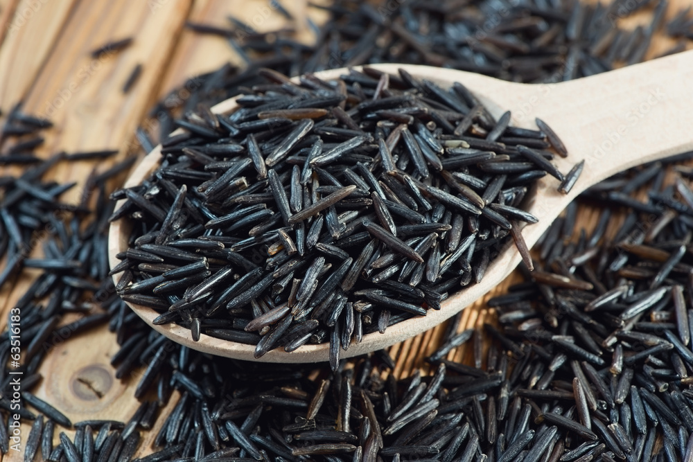Wooden spoon with raw wild rice, horizontal shot Wooden spoon with raw wild rice, horizontal shot