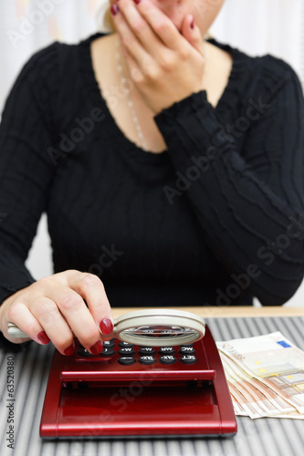 woman watching sum on calculator with magnifying glass and cant photo