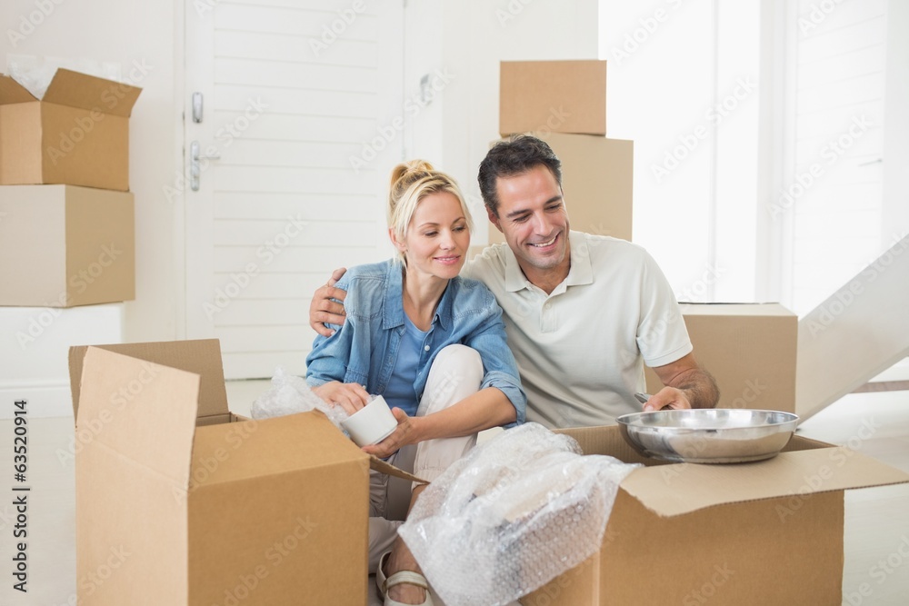 Smiling couple unpacking boxes in a new house