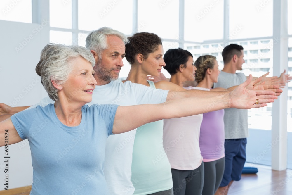 © WavebreakMediaMicro - Class stretching hands in row at yoga class
