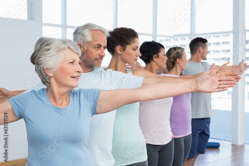 Class stretching hands in row at yoga class