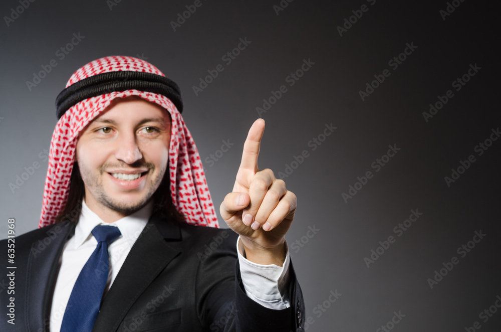 Arab businessman pressing virtual buttons against grey backgroun Arab businessman pressing virtual buttons against grey backgroun