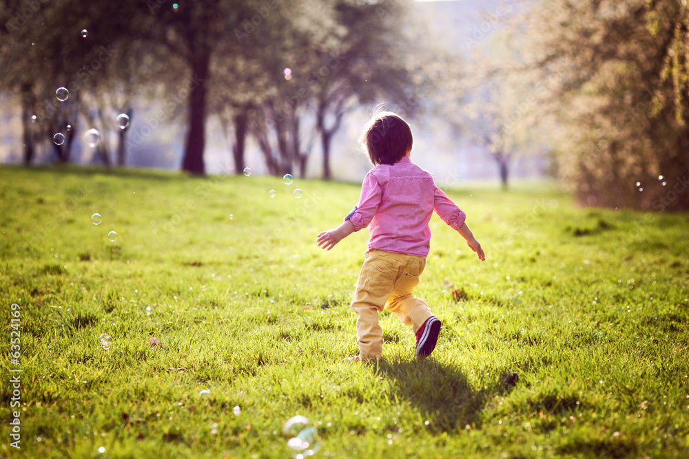 Little boy, running in the park, chasing soap bubbles Little boy, running in the park, chasing soap bubbles