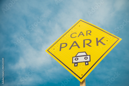 Yellow car park sign with blue sky