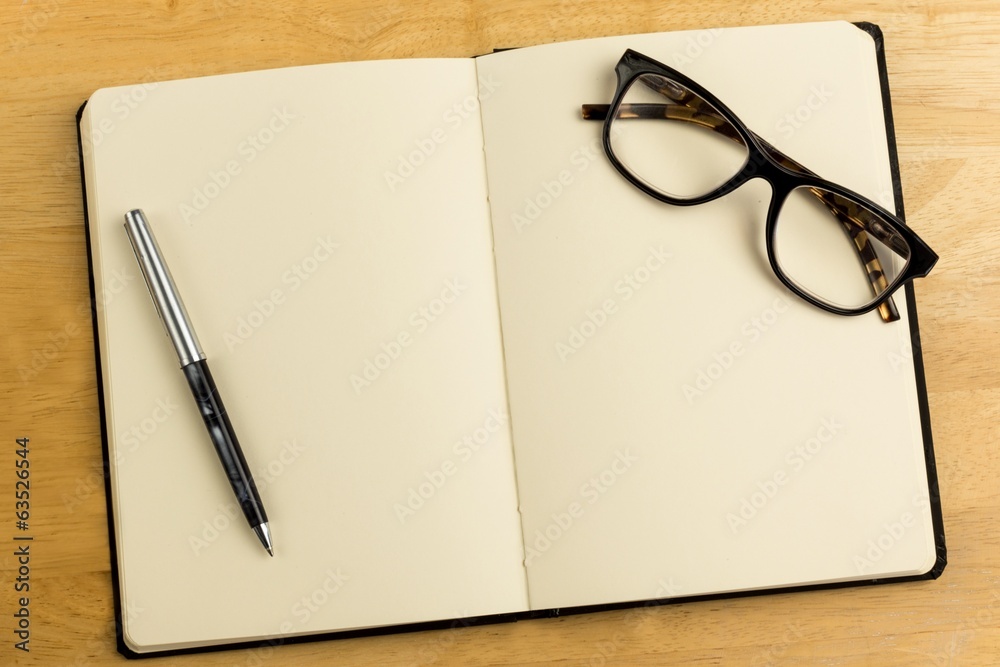 Overhead of open notebook with pen and glasses Overhead of open notebook with pen and glasses