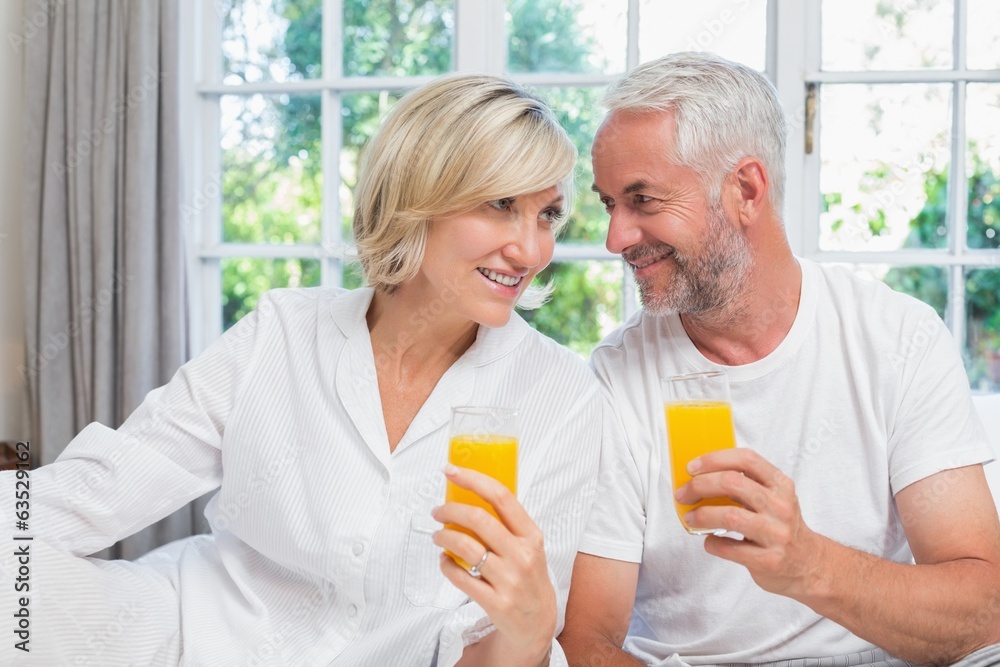 Mature couple holding orange juices at home Mature couple holding orange juices at home