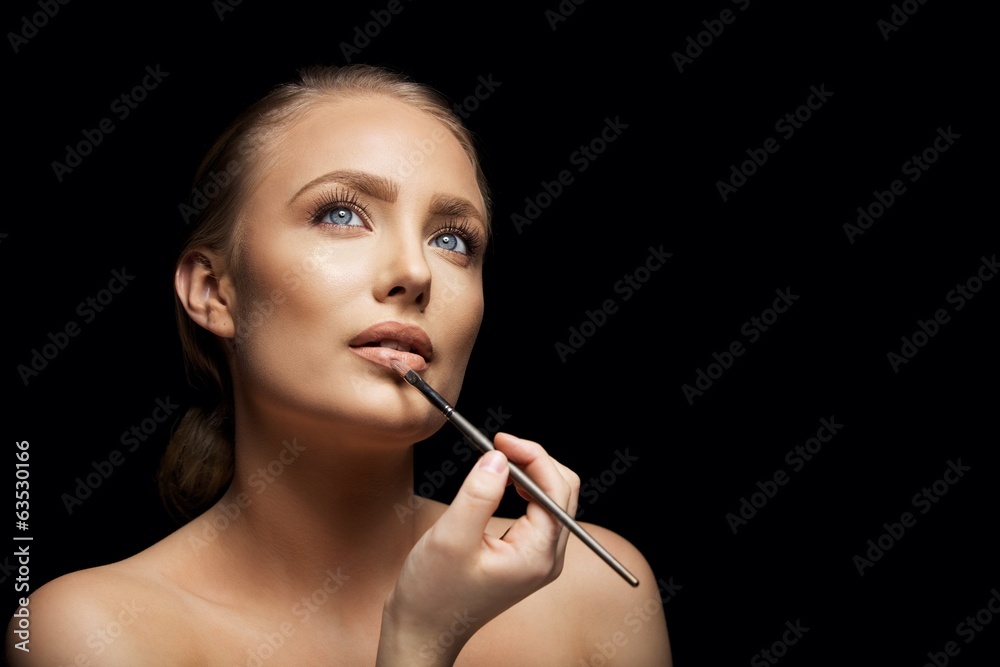 Fototapeta premium Attractive woman applying lip gloss