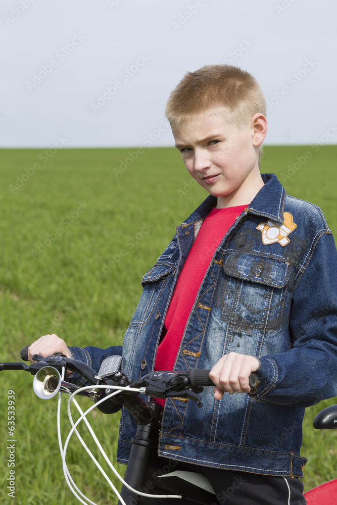 Portrait of the boy with bicycle in the field