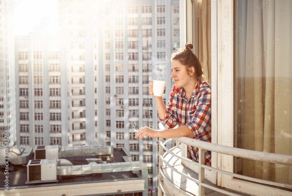 woman drinking coffee and smoking out of window woman drinking coffee and smoking out of window