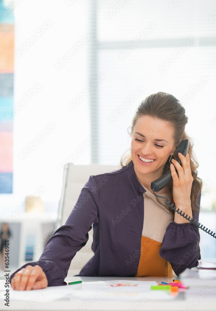 Happy fashion designer talking phone in office Happy fashion designer talking phone in office