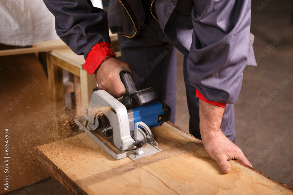 Hands carpenter working with circular saw Hands carpenter working with circular saw