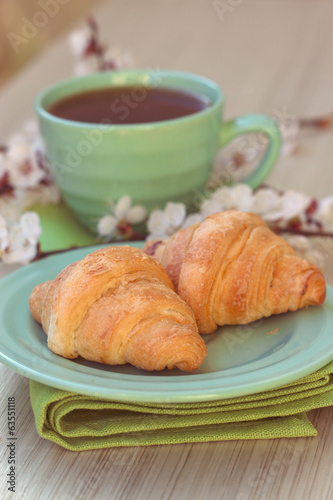 Cup of tea and croissants near blossoming branches