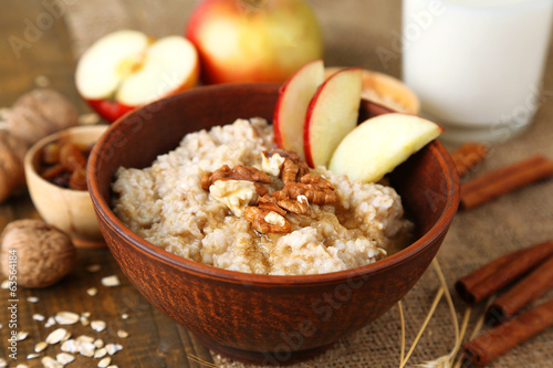 Tasty oatmeal with nuts and apples on wooden table photo