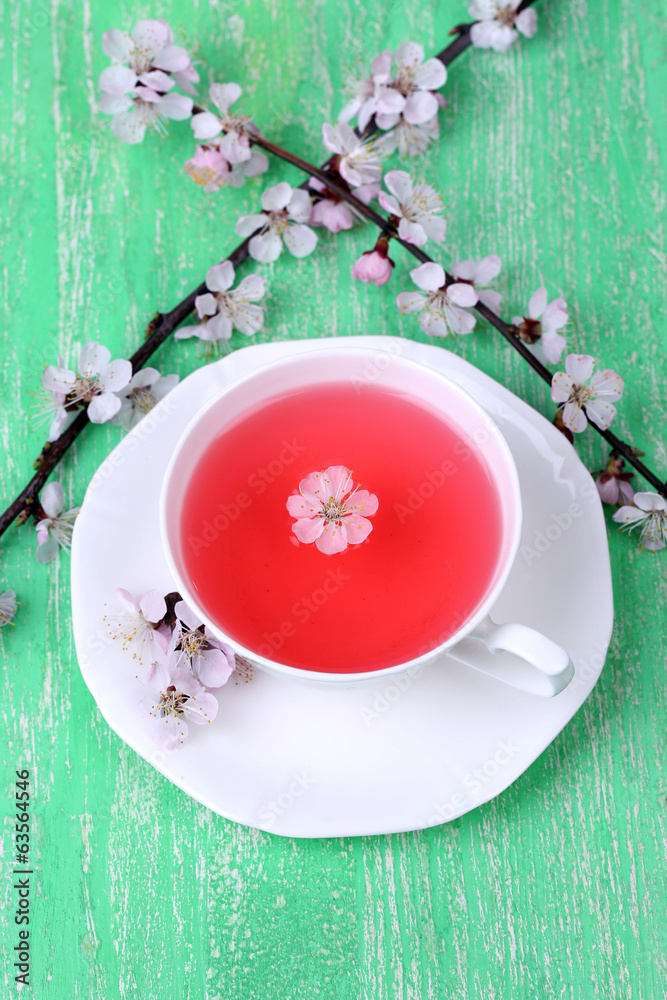 Fragrant tea with flowering branches on wooden table close-up