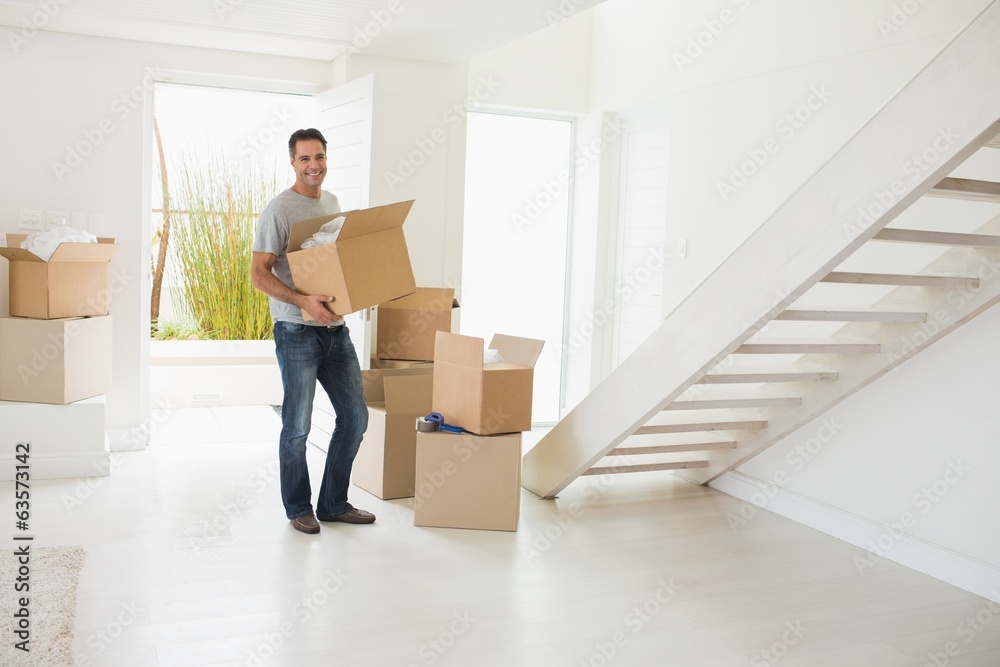 Smiling man carrying boxes in a new house Smiling man carrying boxes in a new house