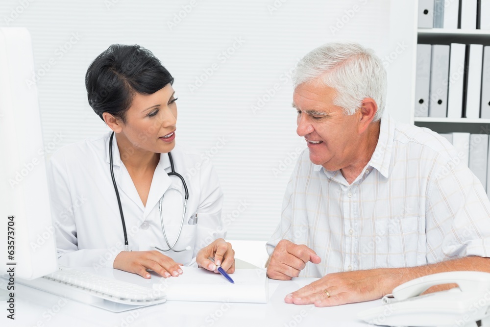Female doctor with male patient reading reports Female doctor with male patient reading reports