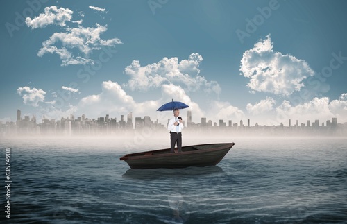 Composite image of happy businessman holding umbrella in a sailb photo