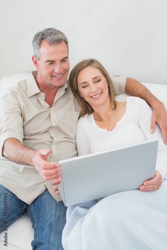 Relaxed couple using laptop on sofa Relaxed couple using laptop on sofa