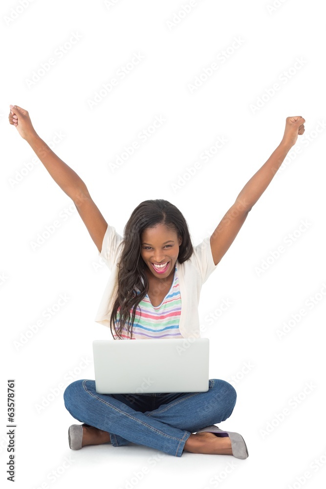 Pretty young woman cheering at camera with laptop sitting on flo Pretty young woman cheering at camera with laptop sitting on flo