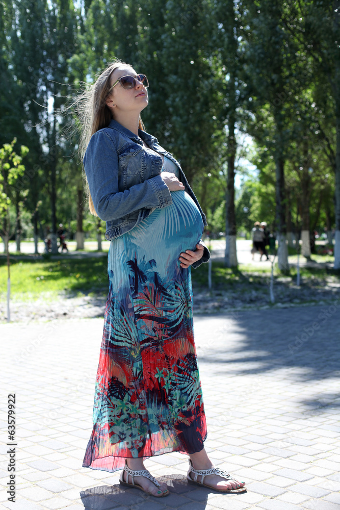 Young pregnant woman in summer park