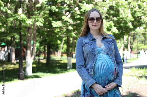 Young pregnant woman in summer park