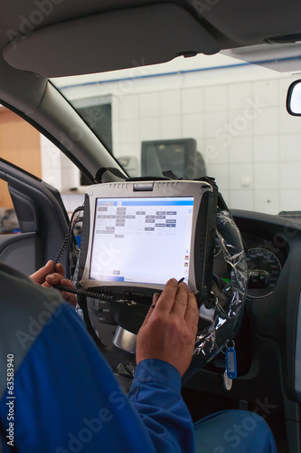Car service worker inside car programming service computer.