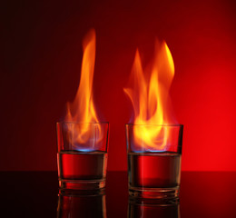 Glasses with burning alcohol on red background