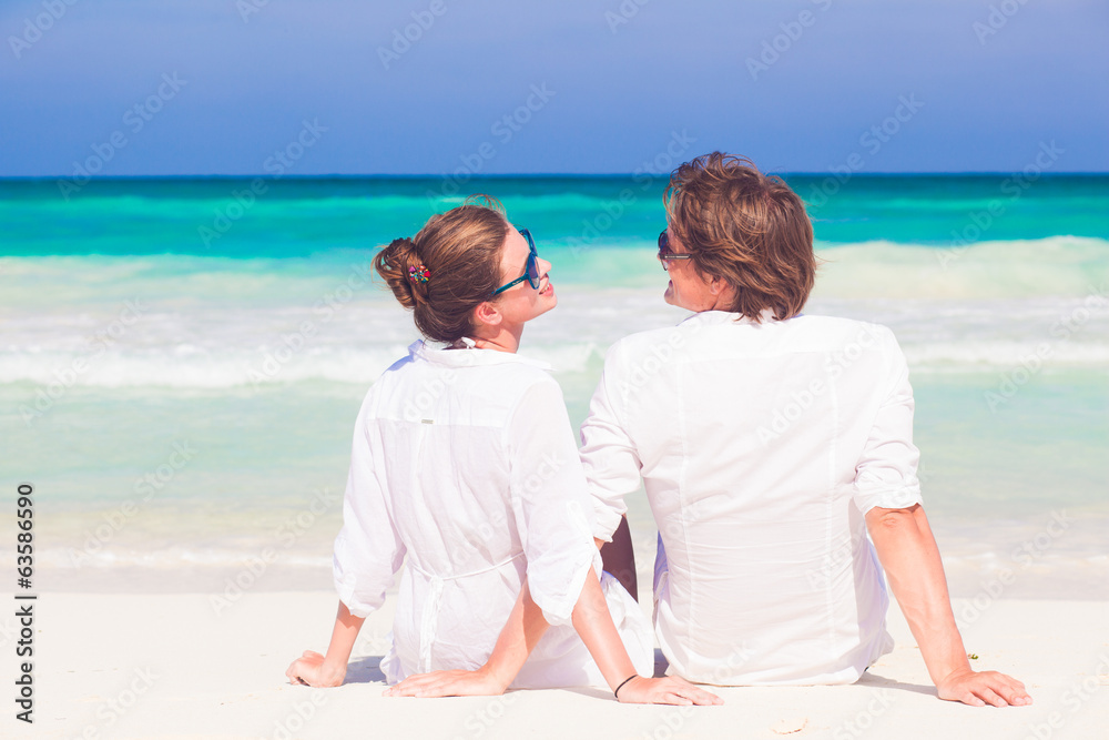 back view of happy young honeymoon couple in white clothes back view of happy young honeymoon couple in white clothes