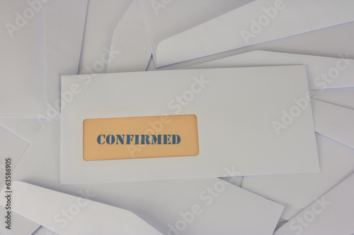 confirmed announcement from white envelope on heap of envelopes