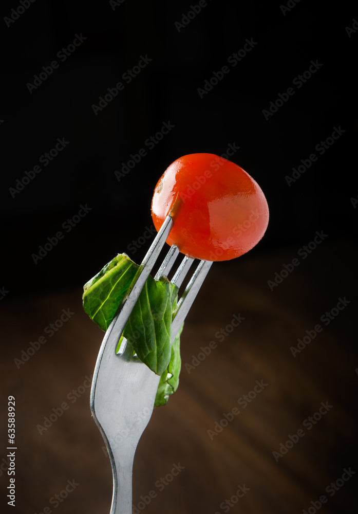 fresh red tomato and salad on a fork.