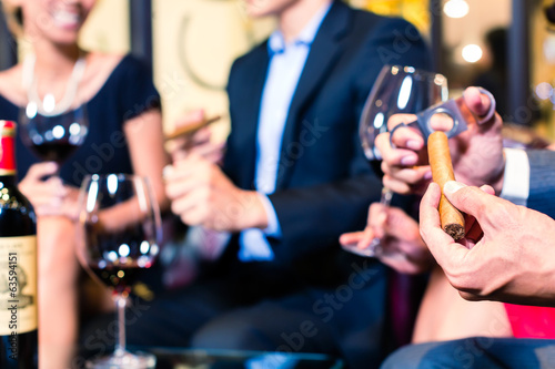 Asian man cutting cigar in restaurant