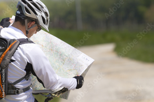 Man with bike checking map and looking around
