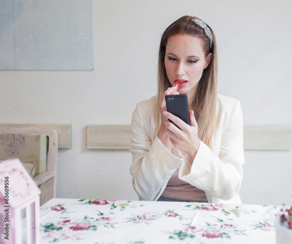 Attractive young woman in the restaurant holding lipstick and lo Attractive young woman in the restaurant holding lipstick and lo