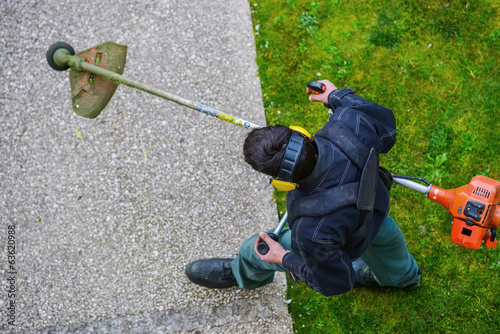 gardener using corded string trimmer in a park photo