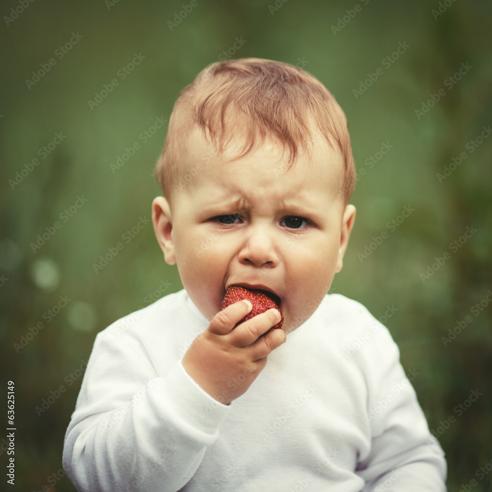 little boy sitting in grass with strawberry little boy sitting in grass with strawberry