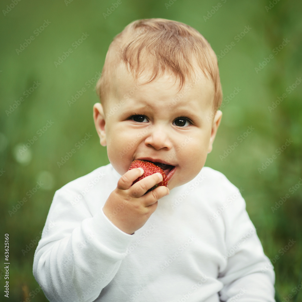 little boy sitting in grass with strawberry little boy sitting in grass with strawberry