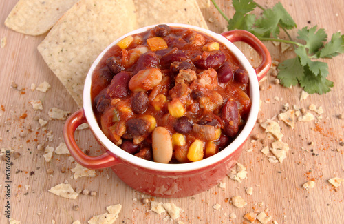 Chili con carne in red bowl with nacho chips and spice