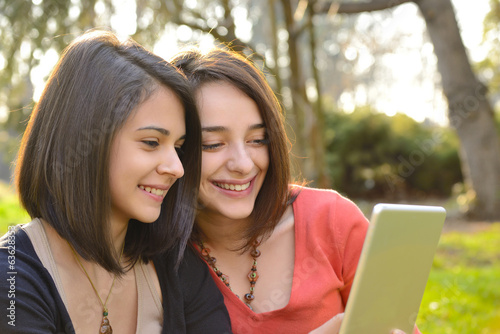 Two beautiful women having fun while browsing a tablet