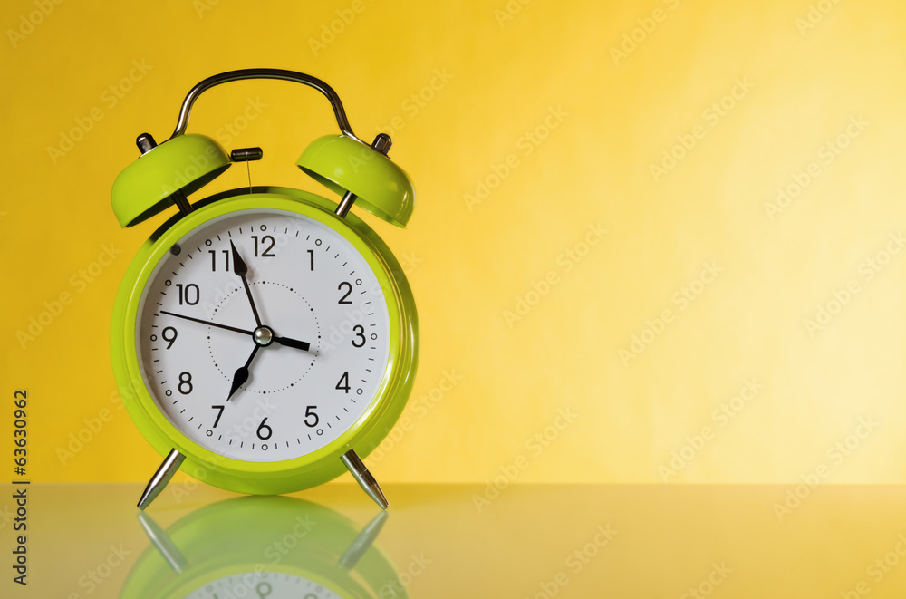 Green alarm clock, close up. A yellow background Green alarm clock, close up. A yellow background