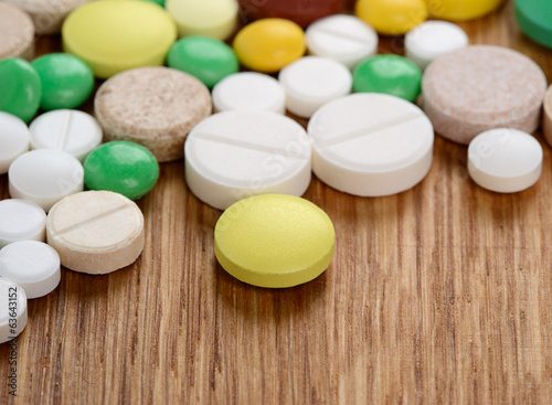 Stack of different pills isolated on wooden background