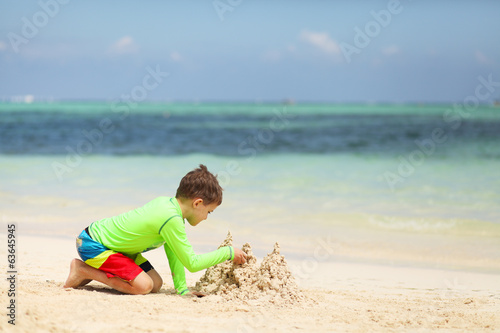 Caucasian boy building sand castle on tropical beach