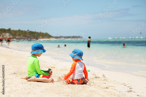 Two caucasian boys playing with sand at tropical beach