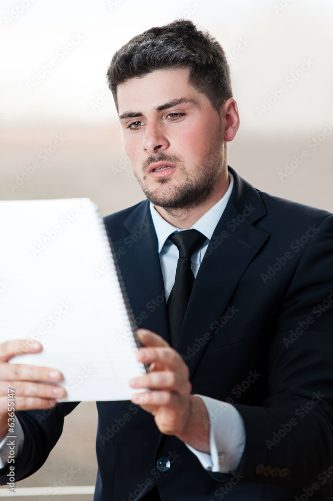 young businessman in black suit reading a notebook young businessman in black suit reading a notebook
