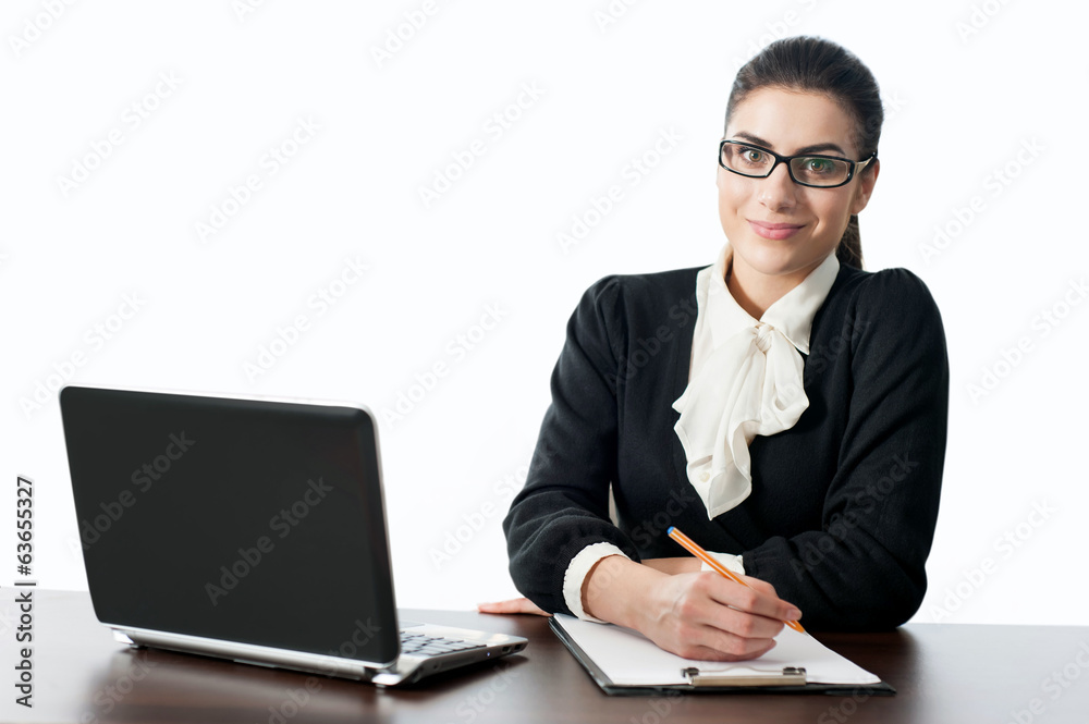 Smiling young female worker sitting at desk with laptop Smiling young female worker sitting at desk with laptop