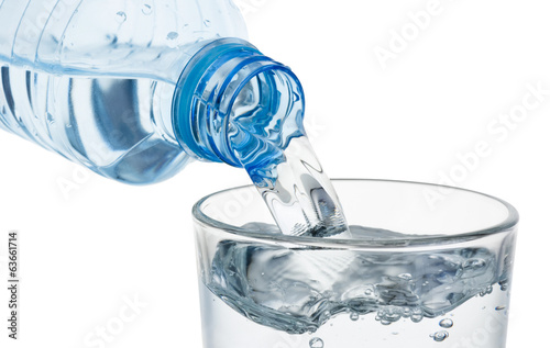 Pouring glass of water from a plastic bottle isolated on white b