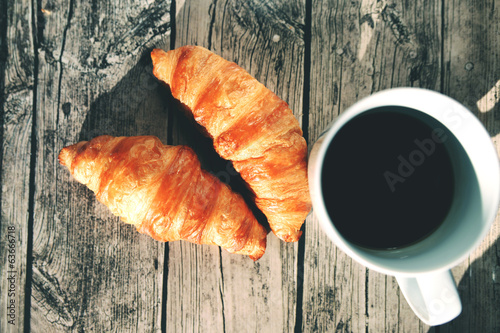 French croissants on a wooden table and black coffee cup