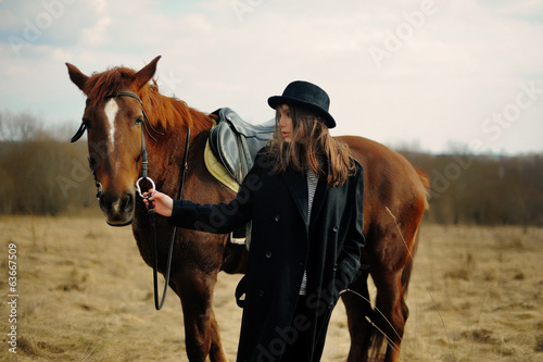 portrait of a beautiful girl with a horse in a hat