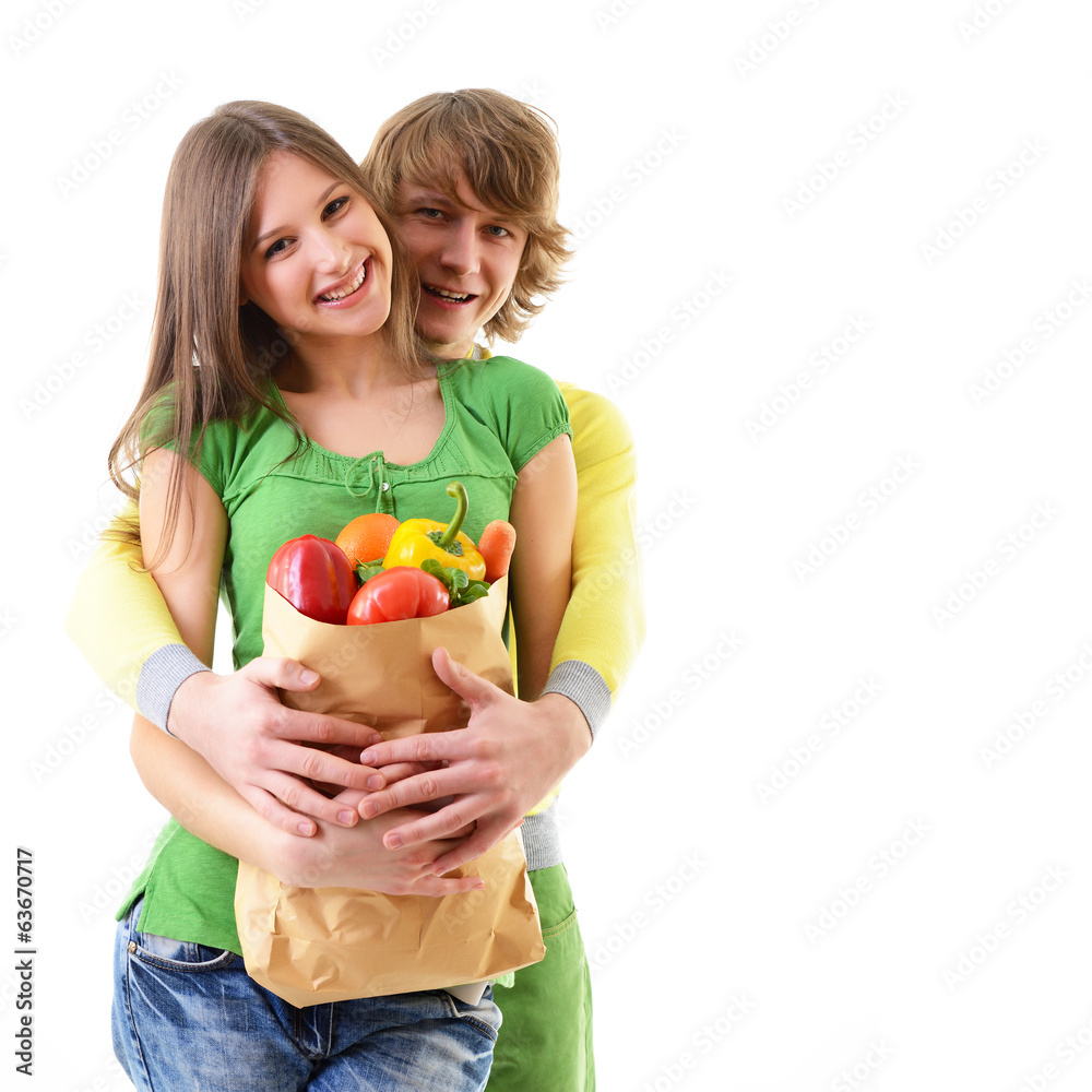 Portrait of a pretty young couple holding a grocery bag and smil