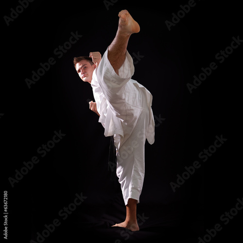 karate man with black belt posing, champion of the world on blac