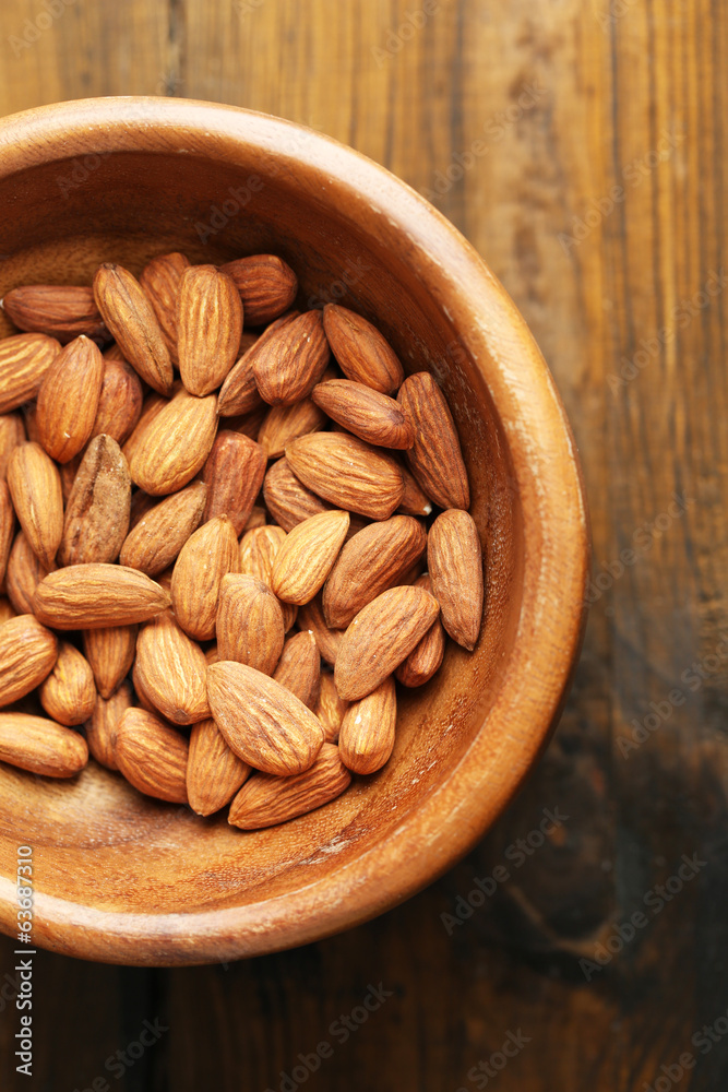 Almonds in bowl on color wooden background Almonds in bowl on color wooden background